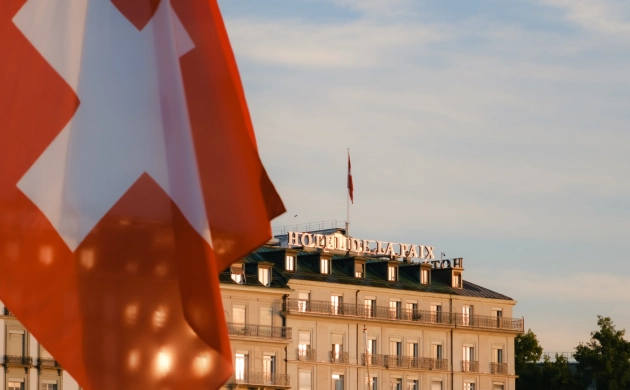 Drapeau suisse devant le Ritz-Carlton Hôtel de la Paix à Genève, lieu du restaurant Dans le Noir ? Genève pour une expérience gastronomique insolite