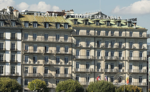 Façade élégante du Ritz-Carlton Hôtel de la Paix à Genève avec vue sur le lac Léman.